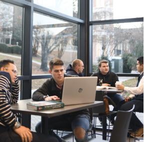 Students at tables working on a laptop